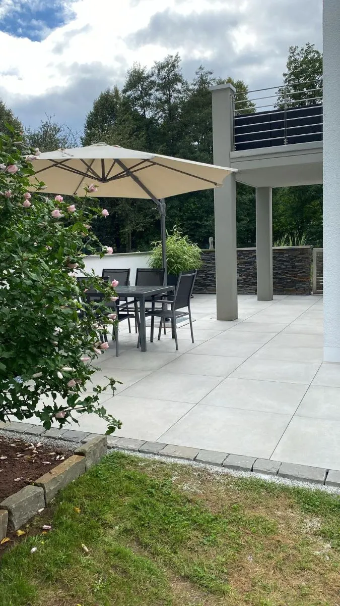 Moderne Terrasse mit Sonnenschirm und stilvollen Gartenmöbeln